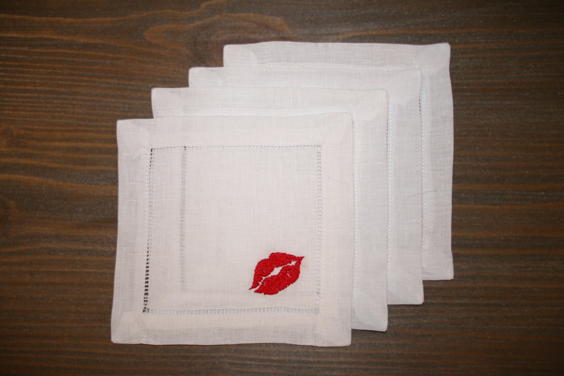 Embroidered cocktail napkins featuring a kiss design in the corner