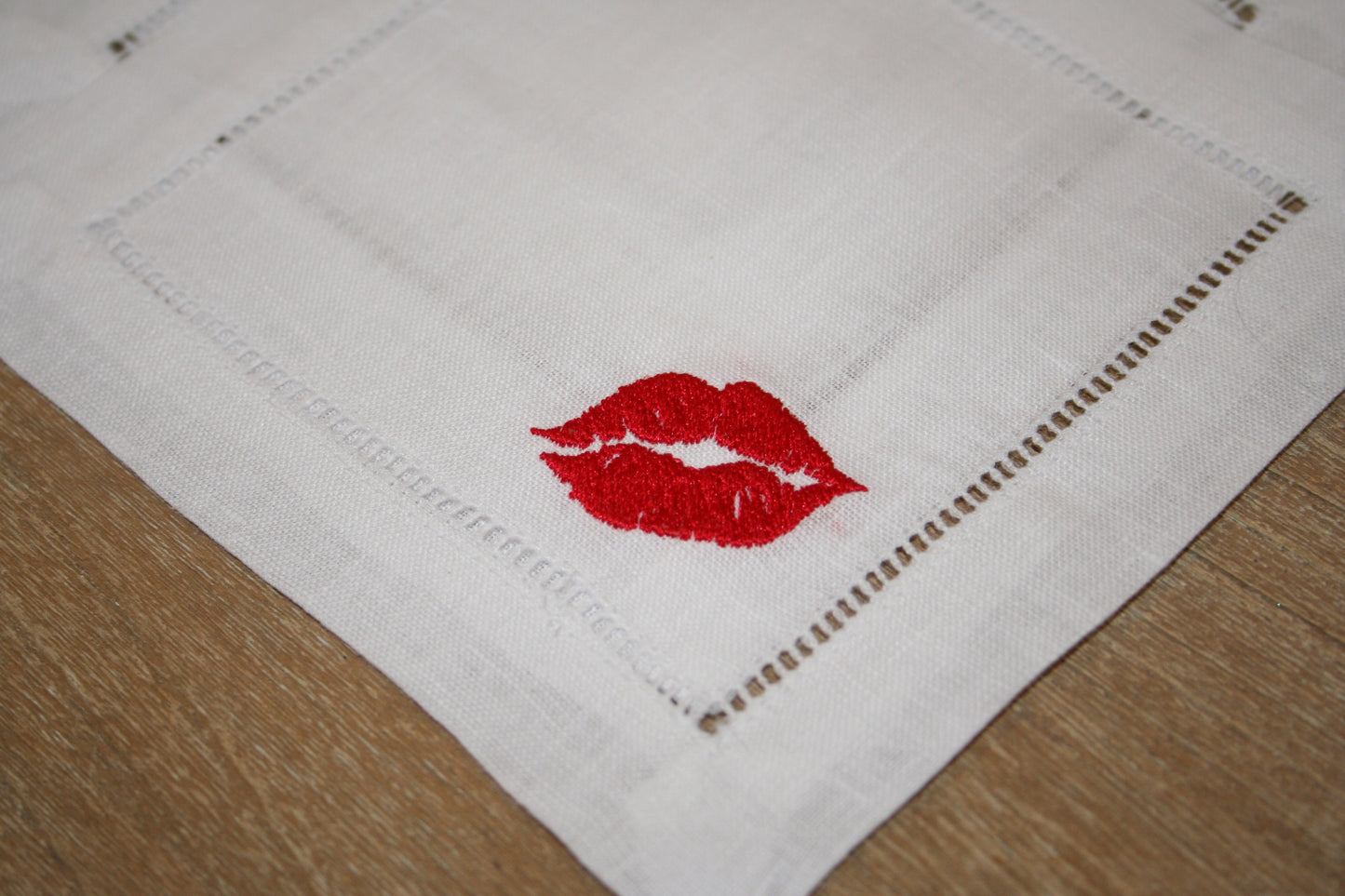 Embroidered cocktail napkins featuring a kiss design in the corner